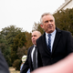 Robert F. Kennedy Jr. walks beside a man framed by other people's arms